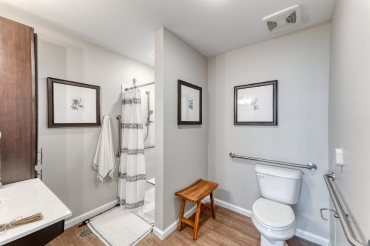 A modern, minimalist bathroom with a shower, toilet, and decorative wall art.