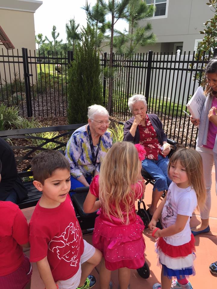 Children interacting with seniors outdoors in a community setting.