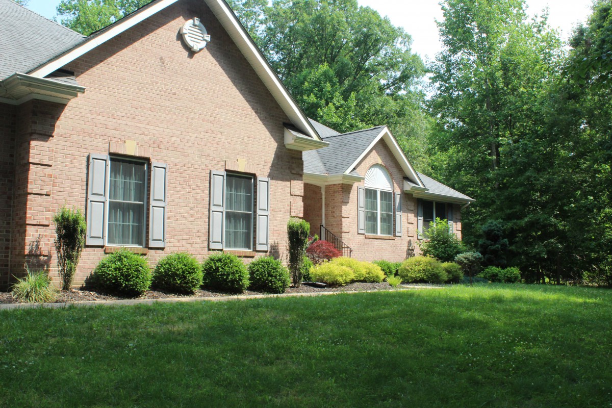A brick house with a well-maintained front yard and shrubs.