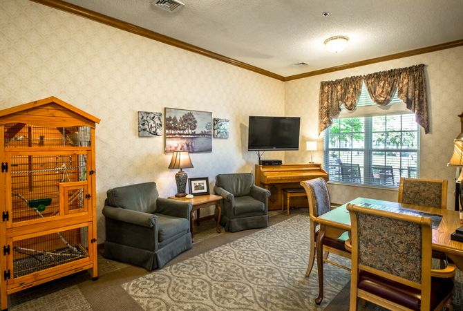 A cozy living room with comfortable seating, a television, and a piano.