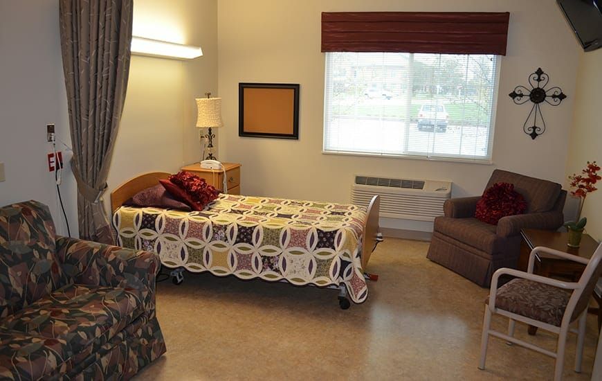 A simple hospital room with a single bed, lamp, and window.