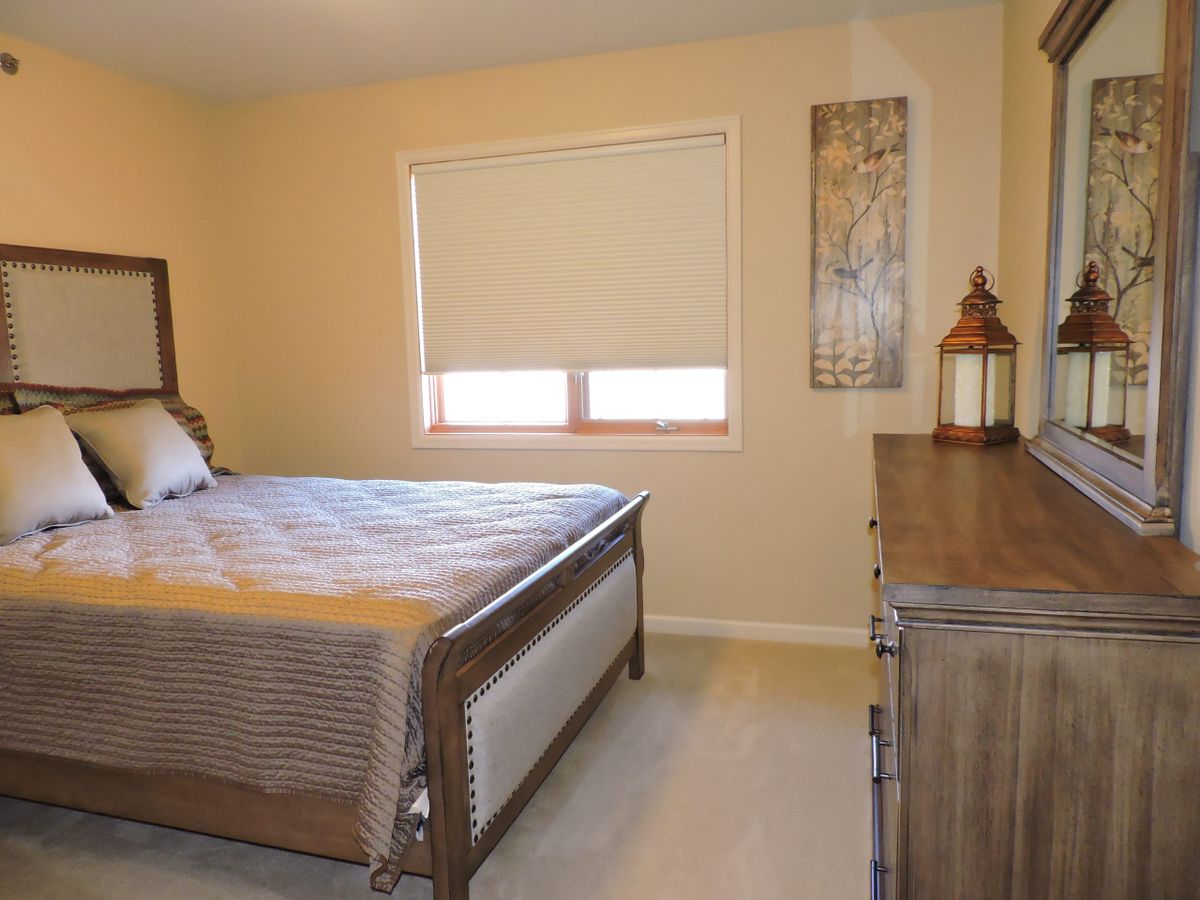 A cozy bedroom with a bed, dresser, and window providing natural light.
