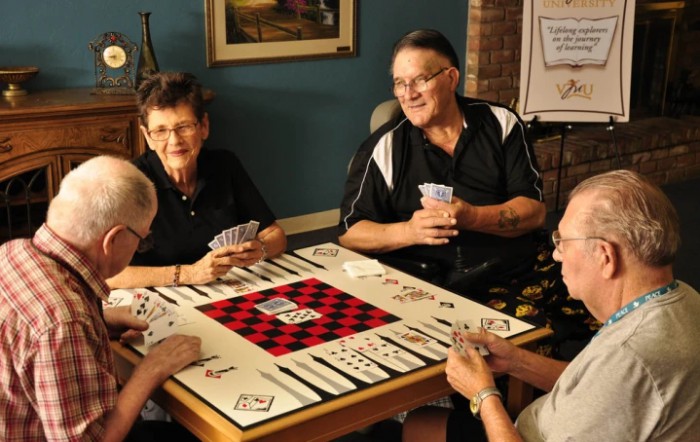 A group of people playing cards and enjoying a board game together indoors.