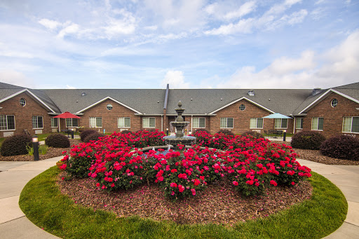 A beautiful garden featuring vibrant flowers and a decorative fountain in front of residential buildings.