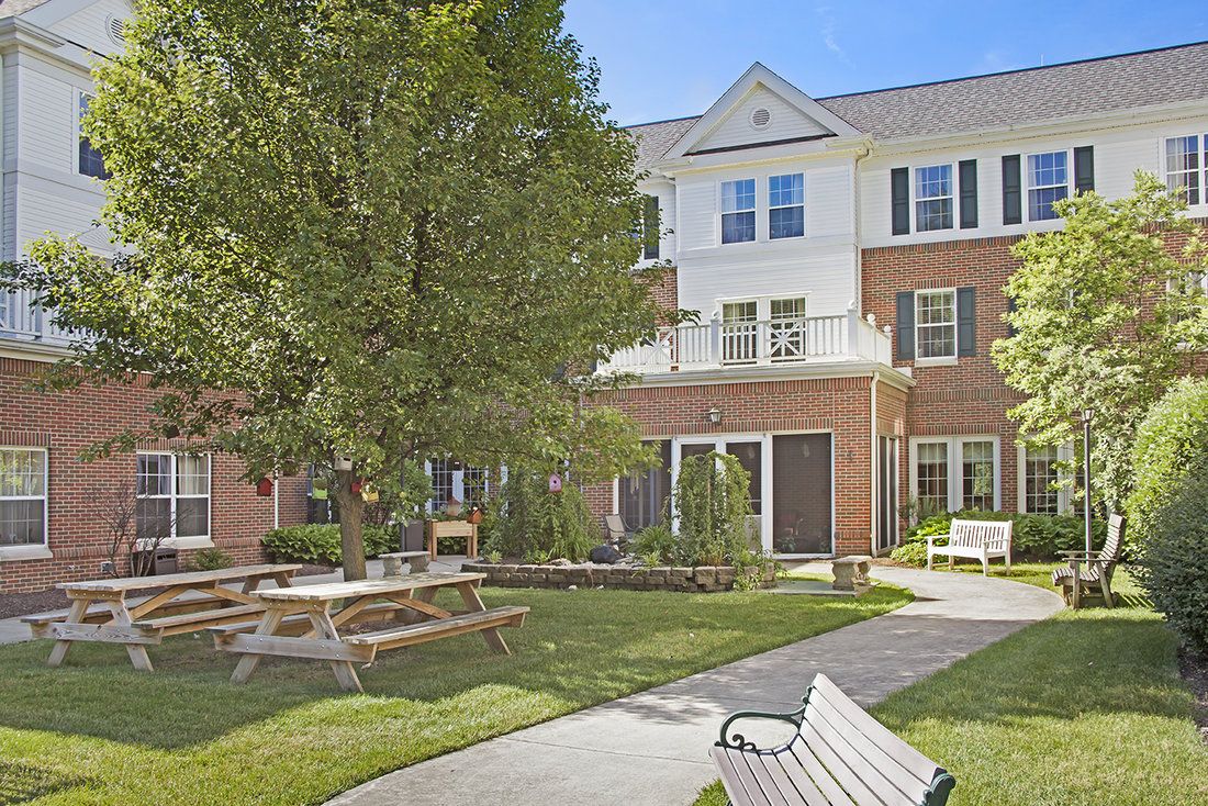 A peaceful residential courtyard with benches, trees, and a well-maintained garden.