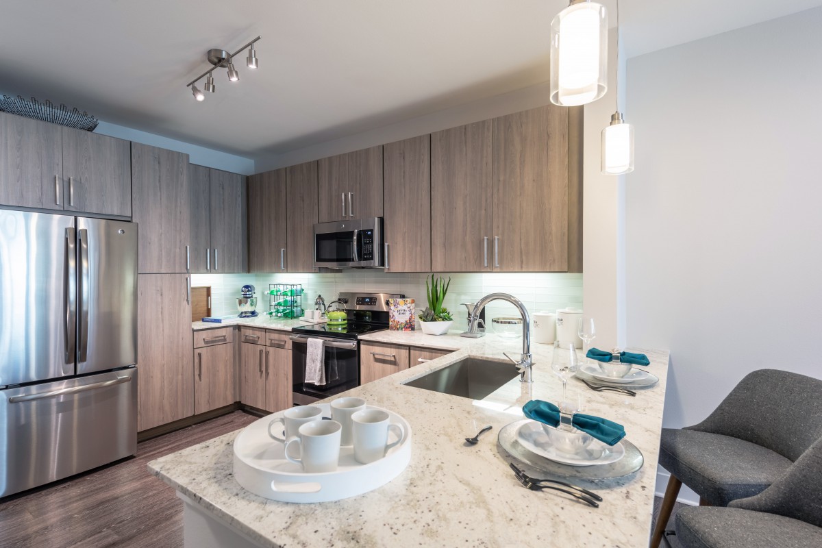 A modern kitchen interior featuring wooden cabinets and a sleek countertop with dining setup.