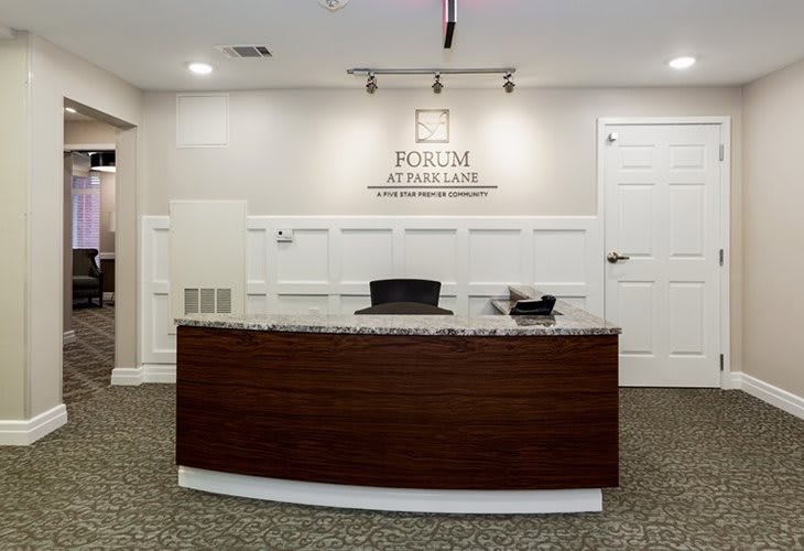 A modern office reception area with a wooden desk and decorative wall paneling.