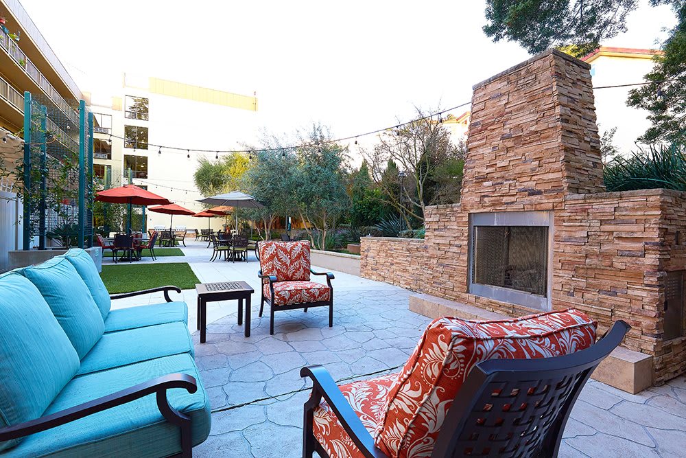 A cozy outdoor patio with comfortable seating and a stone fireplace.