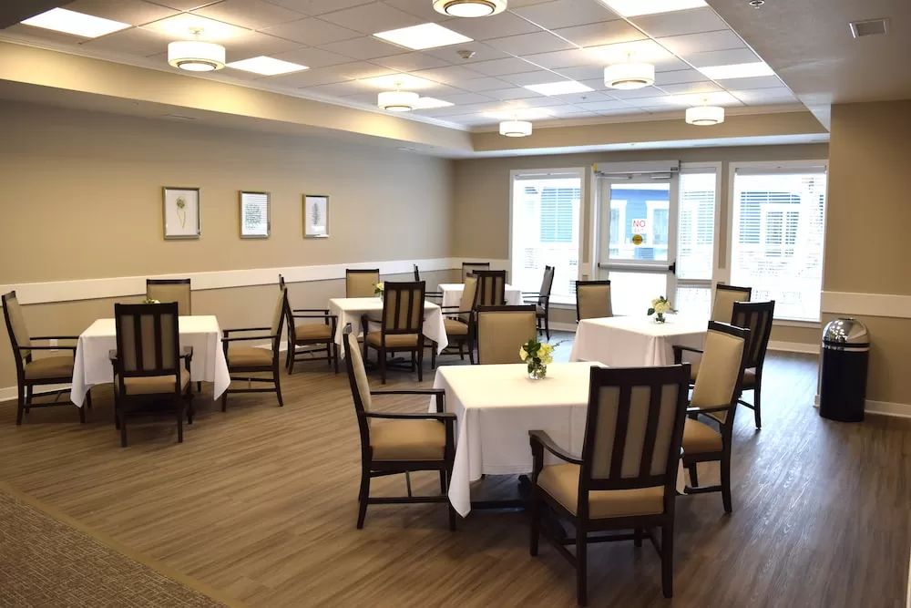 An empty dining room with neatly arranged tables and chairs, illuminated by overhead lights.