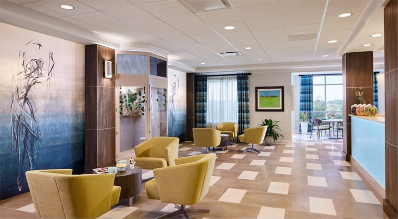 A modern lobby with yellow chairs and artwork on the walls.