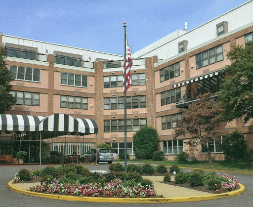 A well-maintained hotel featuring a flagpole and colorful flower beds in the foreground.