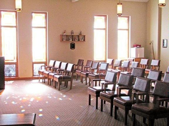 A serene chapel interior with rows of chairs and natural lighting.
