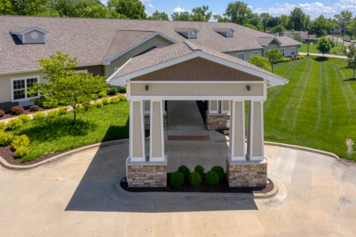 A covered entrance with columns and a driveway leading to the building.
