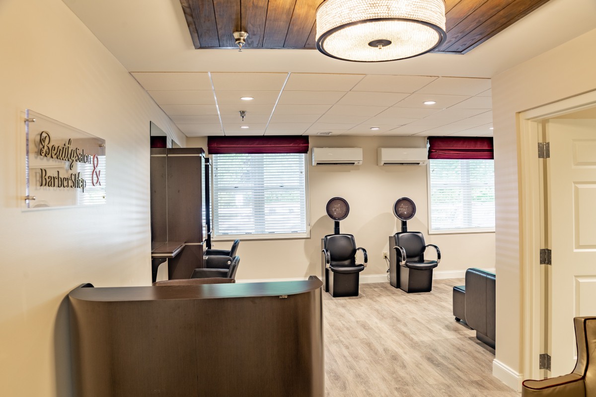 A modern salon interior featuring a waiting area with hair dryer stations and comfortable seating.
