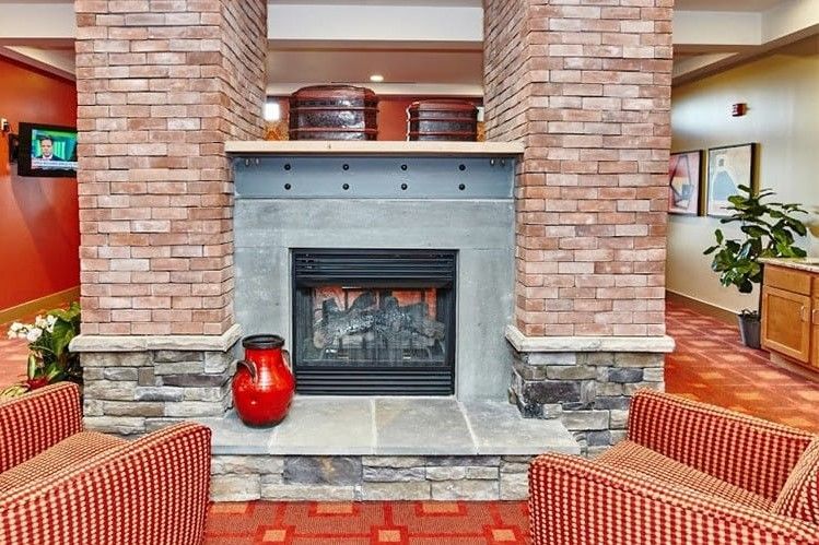 A cozy lounge area featuring a brick fireplace and a decorative red vase.