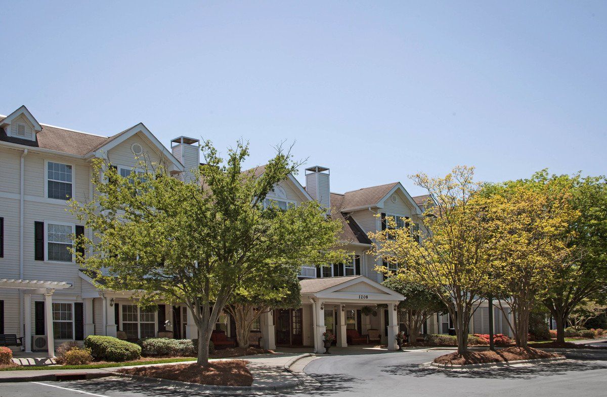 A multi-story residential building surrounded by trees under a clear sky.