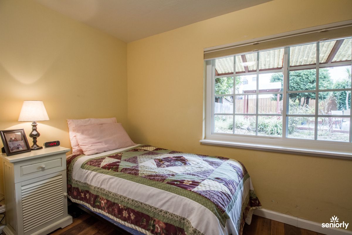 A cozy bedroom with a single bed and a colorful quilt by the window.