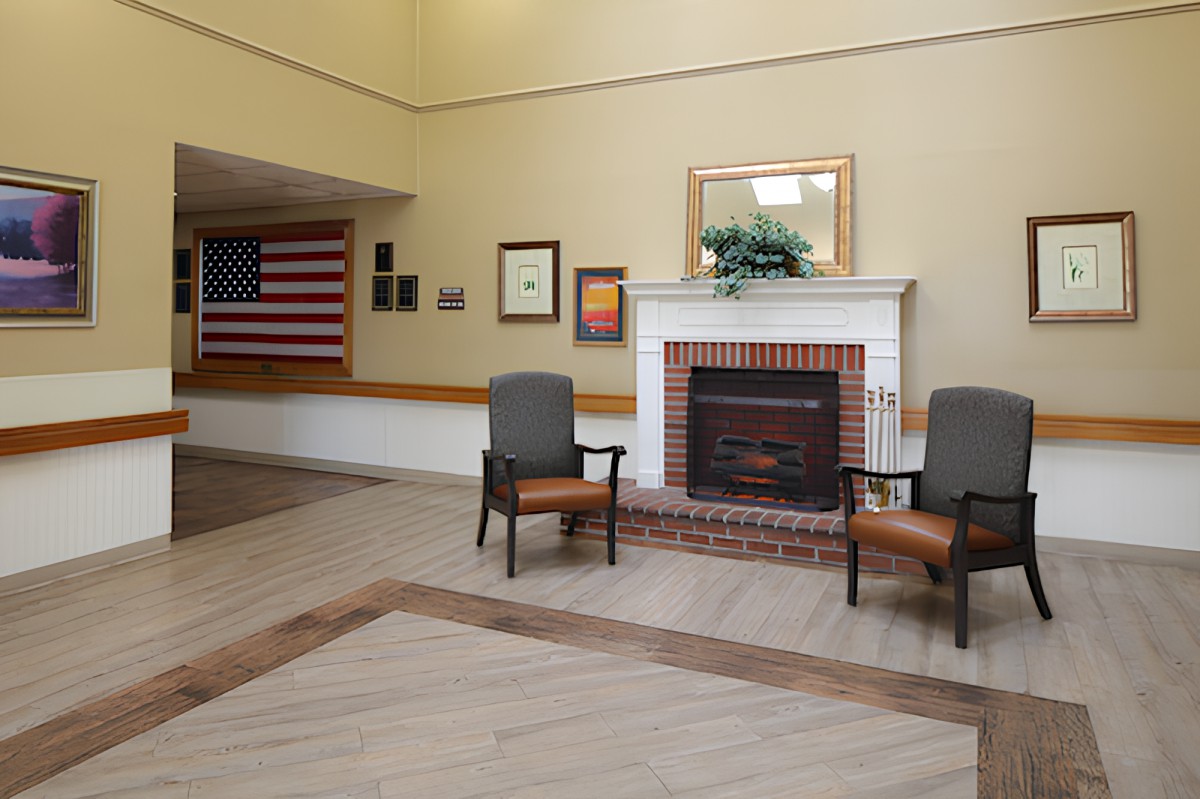 A lobby area featuring a brick fireplace, two chairs, and an American flag on the wall.