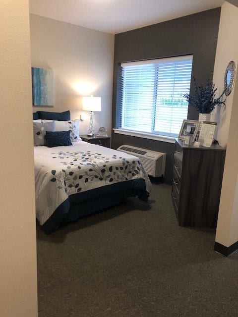 A cozy bedroom with a neatly made bed, featuring decorative pillows and a lamp by the bedside.