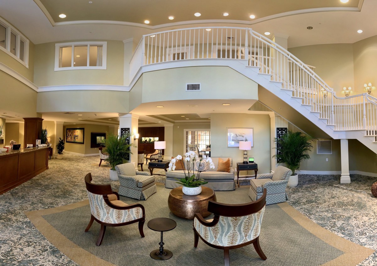 A spacious and elegantly designed lobby area with comfortable seating, indoor plants, and a staircase leading to the upper level.