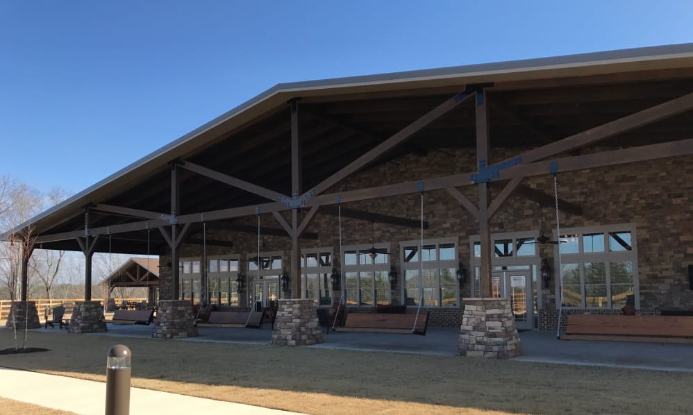 A spacious pavilion with stone columns and a wooden roof structure under a clear blue sky.