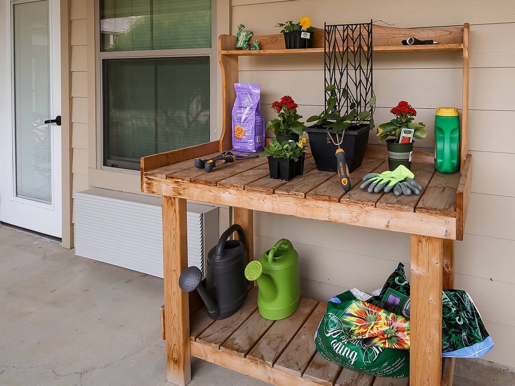 An outdoor potting bench with gardening supplies and potted plants.