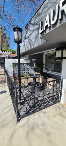 A charming outdoor space featuring a decorative fountain surrounded by lush greenery and an intricate fence.