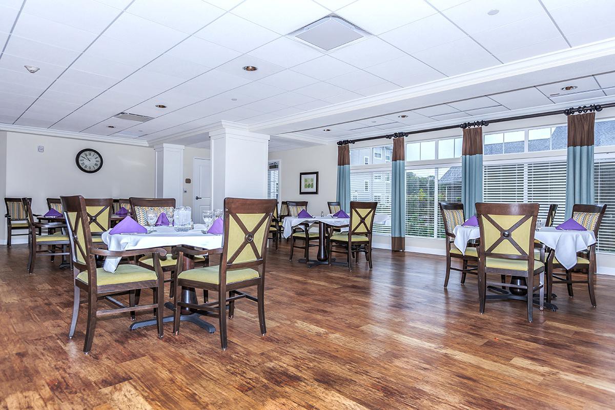 A bright and spacious dining area with wooden floors and neatly arranged tables and chairs.