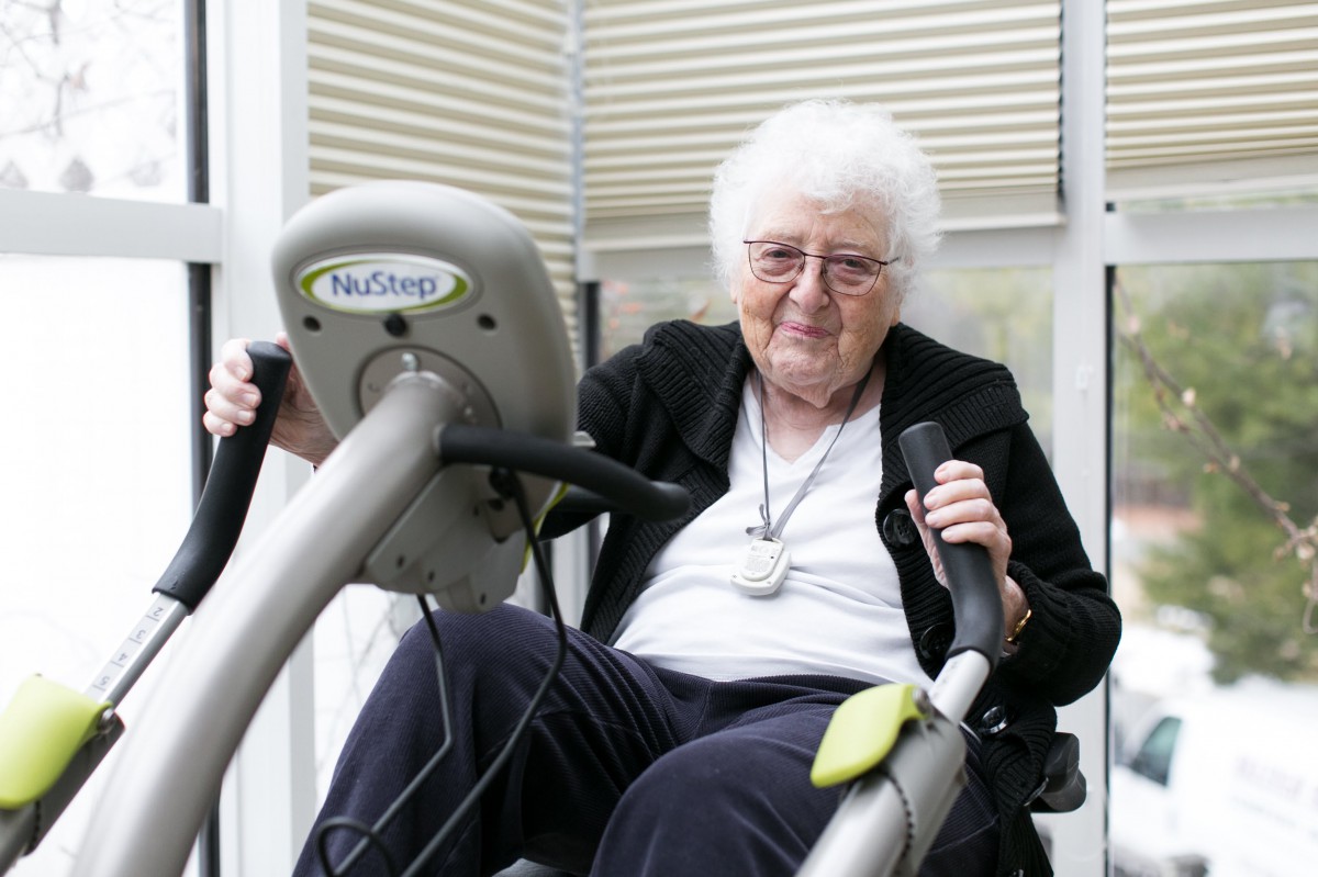 An elderly woman exercising on fitness equipment indoors, highlighting an active lifestyle.