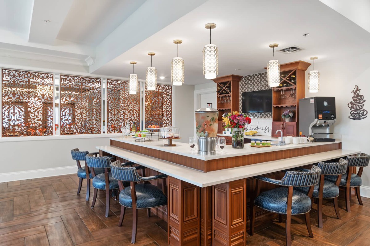 A modern kitchen and dining area featuring wooden furniture, pendant lighting, and blue bar stools.