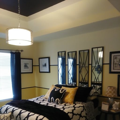 A stylishly decorated bedroom with patterned bedding, mirrors above the bed, and modern lighting.