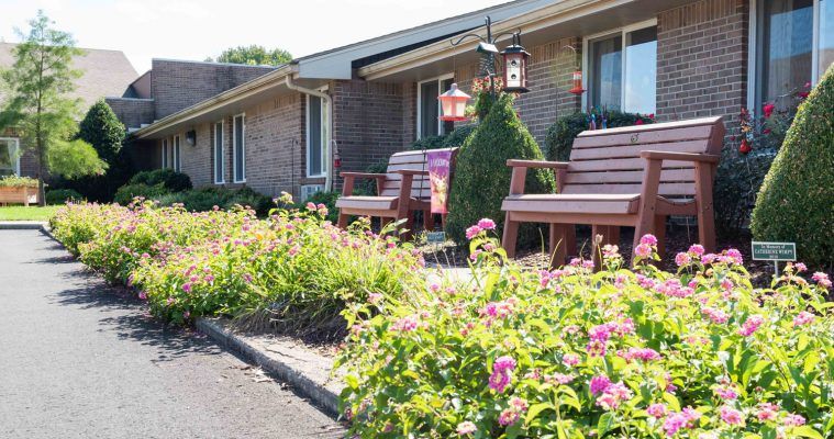 A cozy brick house with a beautifully landscaped garden featuring flowers and outdoor seating.