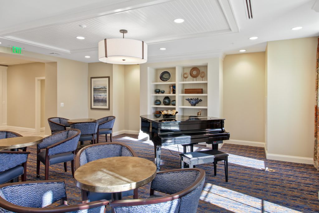 A well-lit lounge with a grand piano and comfortable seating areas.