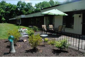 A patio area with outdoor furniture and a large umbrella, surrounded by landscaped gardens.