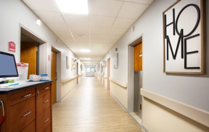 A clean, well-lit hospital corridor lined with doors on either side.