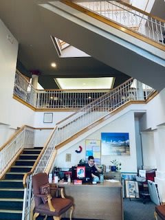 A spacious office building interior with a reception desk and a grand staircase.