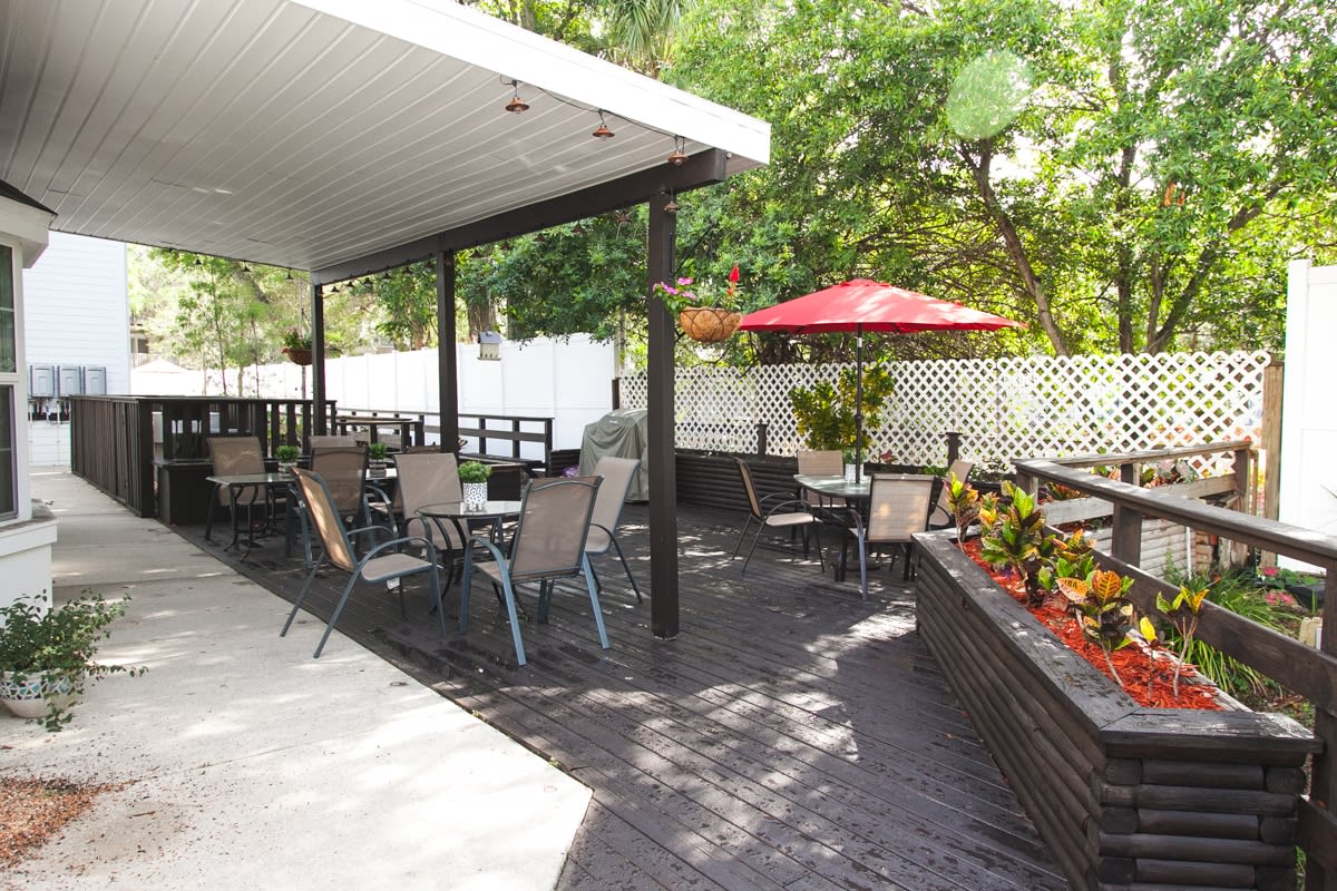 An inviting outdoor patio area with seating, plants, and an umbrella for shade.