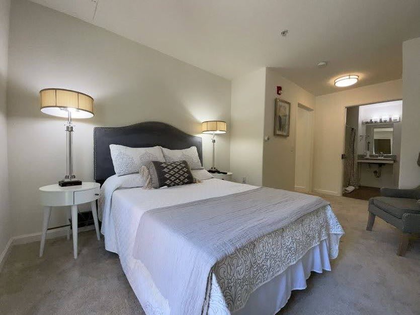 A modern bedroom with a neatly made bed, stylish lamps, and soft lighting.