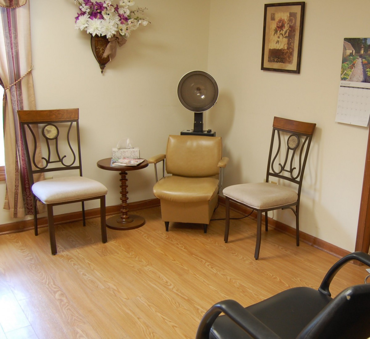 A cozy waiting area in a salon featuring chairs and a vintage hair dryer.