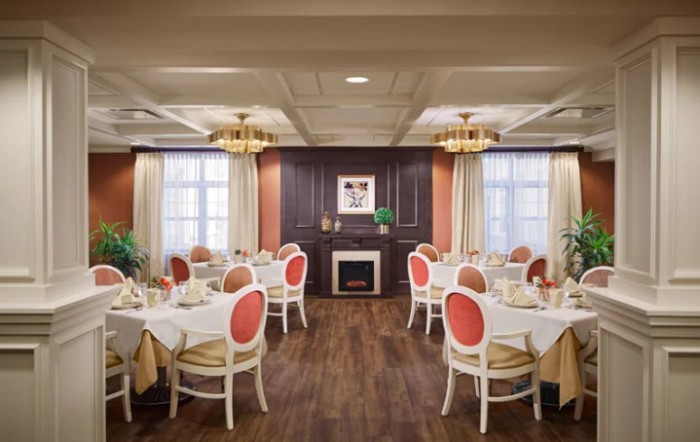 An elegant dining room interior with neatly arranged tables and chairs, featuring classic decor and chandeliers.