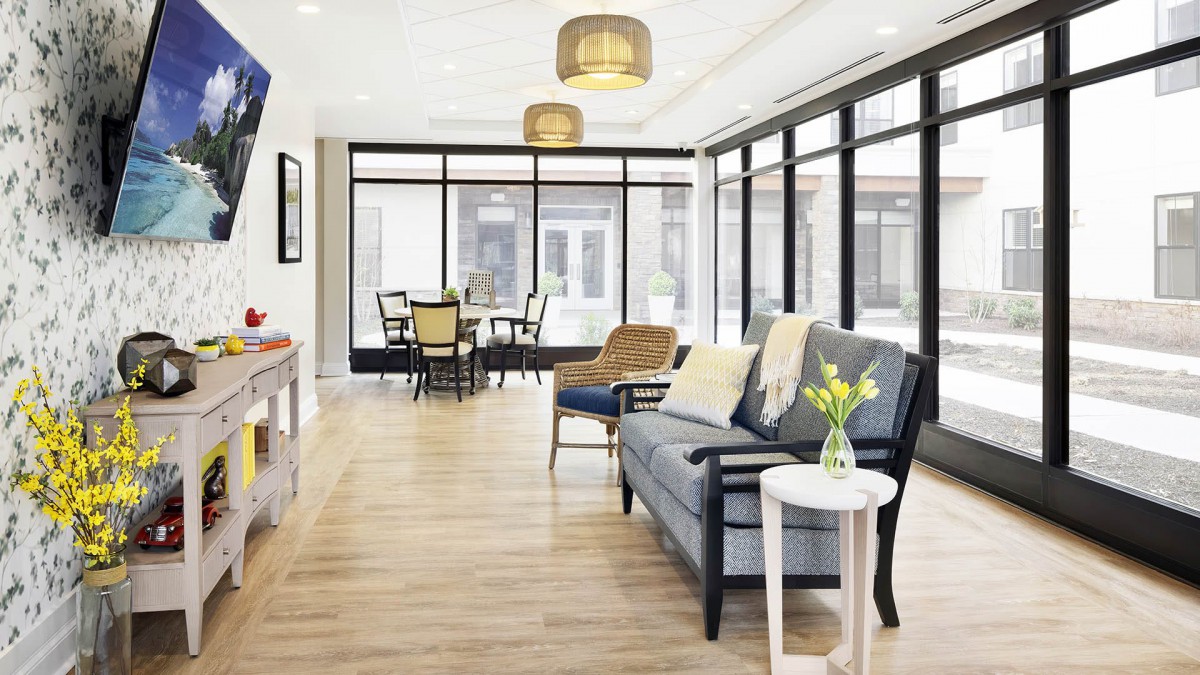 A modern and bright living room with large windows, comfortable seating, and a dining area.