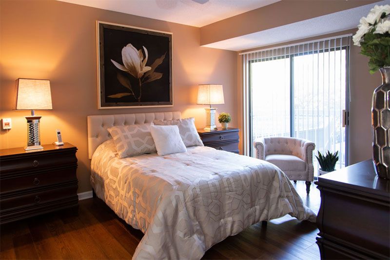 A cozy bedroom with elegant decor, featuring a comfortable bed, bedside lamp, and artwork above the headboard.