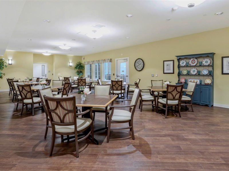 A spacious dining area with multiple tables and chairs, featuring elegant interior design and wood flooring.