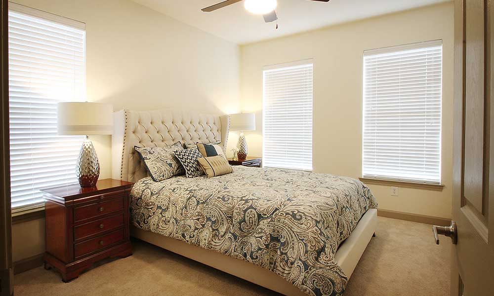 A cozy bedroom with a patterned bedspread and neutral tones.