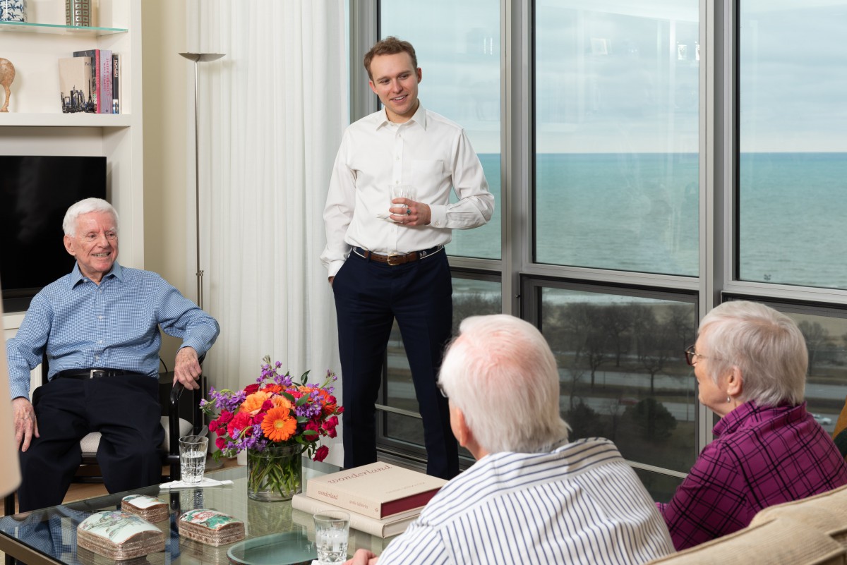 A group of people having a casual business meeting in an office with a view.