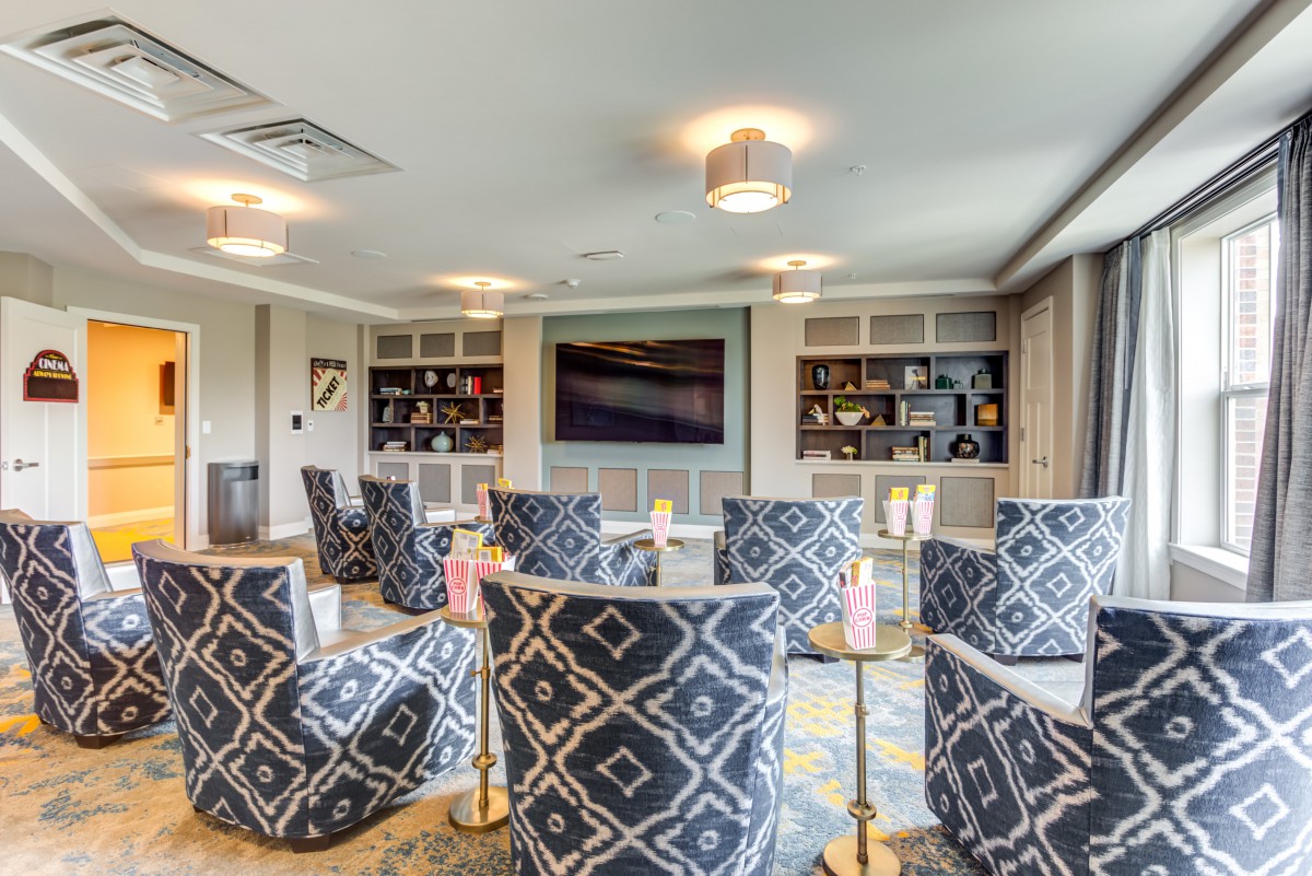 A modern living room with patterned chairs, a large television, and built-in bookshelves.