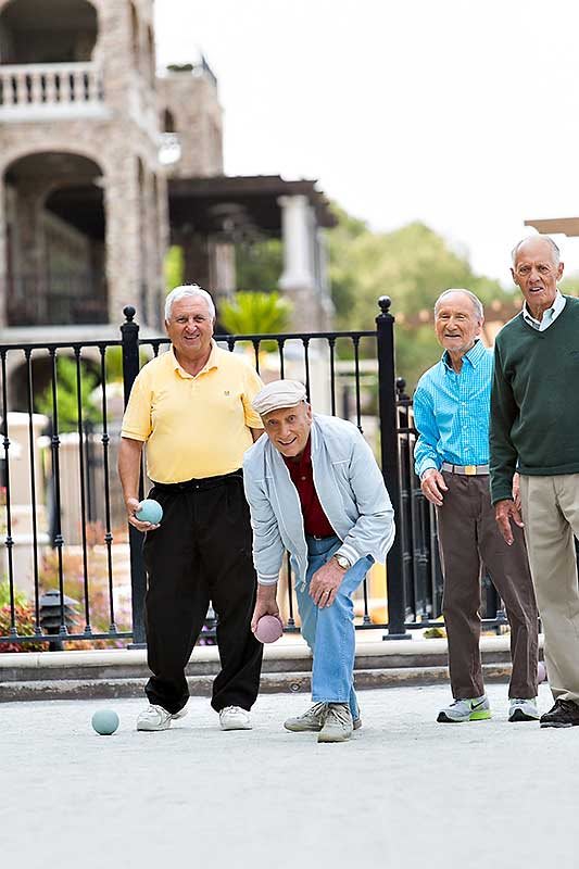 A group of elderly men enjoying a game of bocce outdoors.