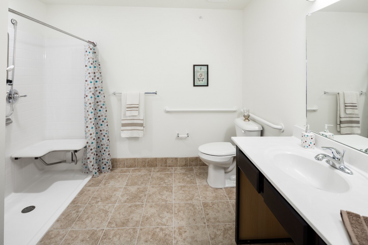 A modern bathroom with a shower, toilet, and sink.