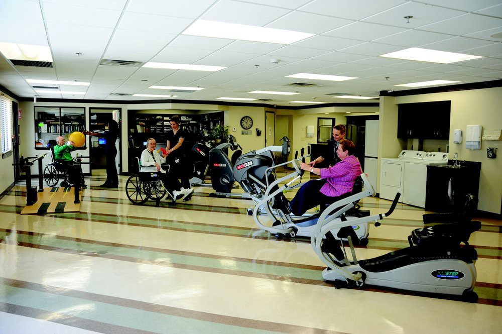 A group of people engaging in various exercises using gym equipment, including a person in a wheelchair.