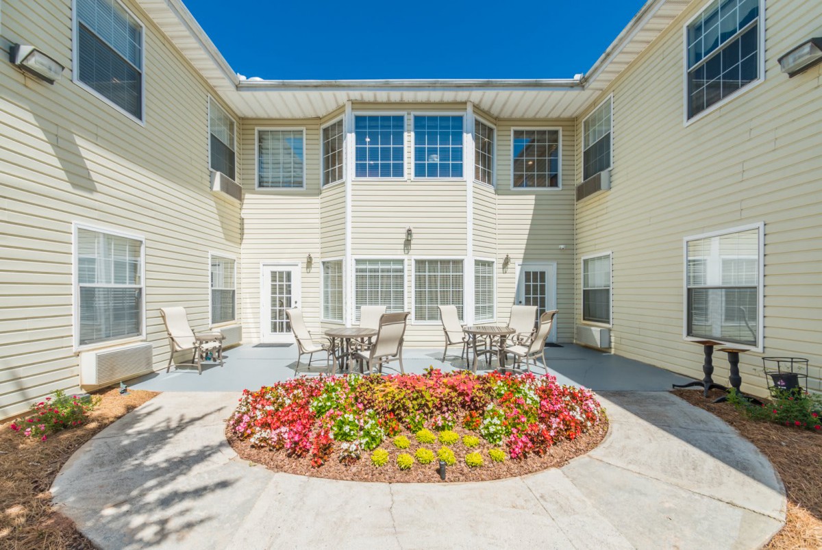 A bright courtyard with colorful flowers and outdoor seating areas.